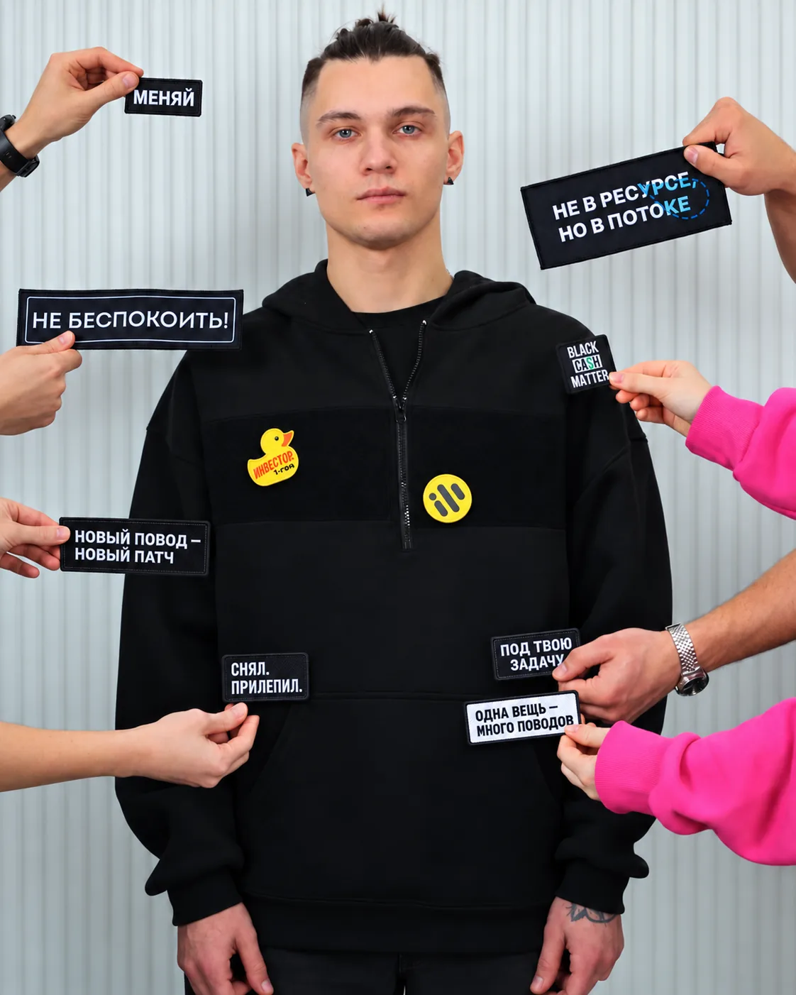 Hands placing lettered patches onto a hoodie's velcro zone